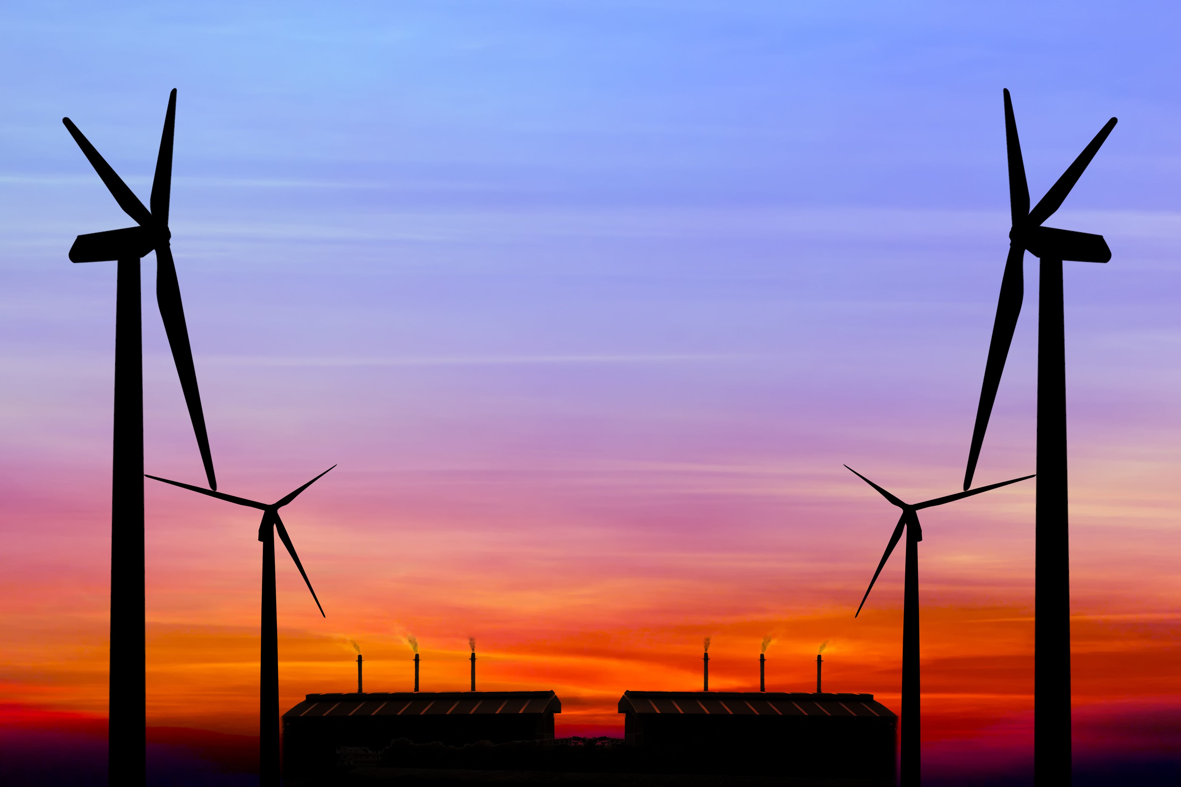 Silhouette of wind turbines against a colorful sunset sky, symbolizing renewable energy.