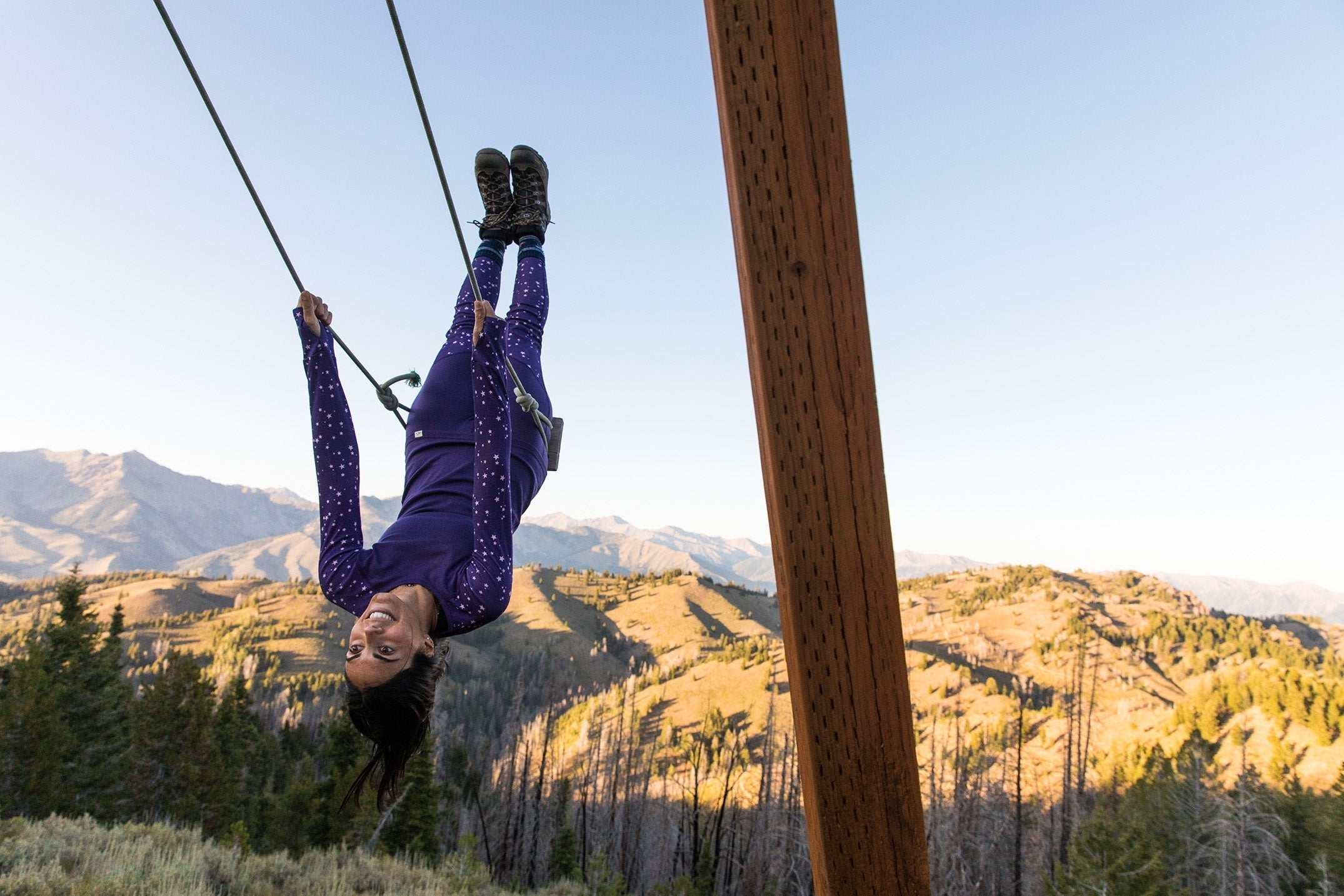 Person zip lining in a mountainous landscape during sunset