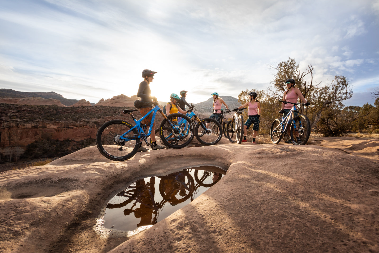 Group of women mountain biking in a desert landscape during sunset