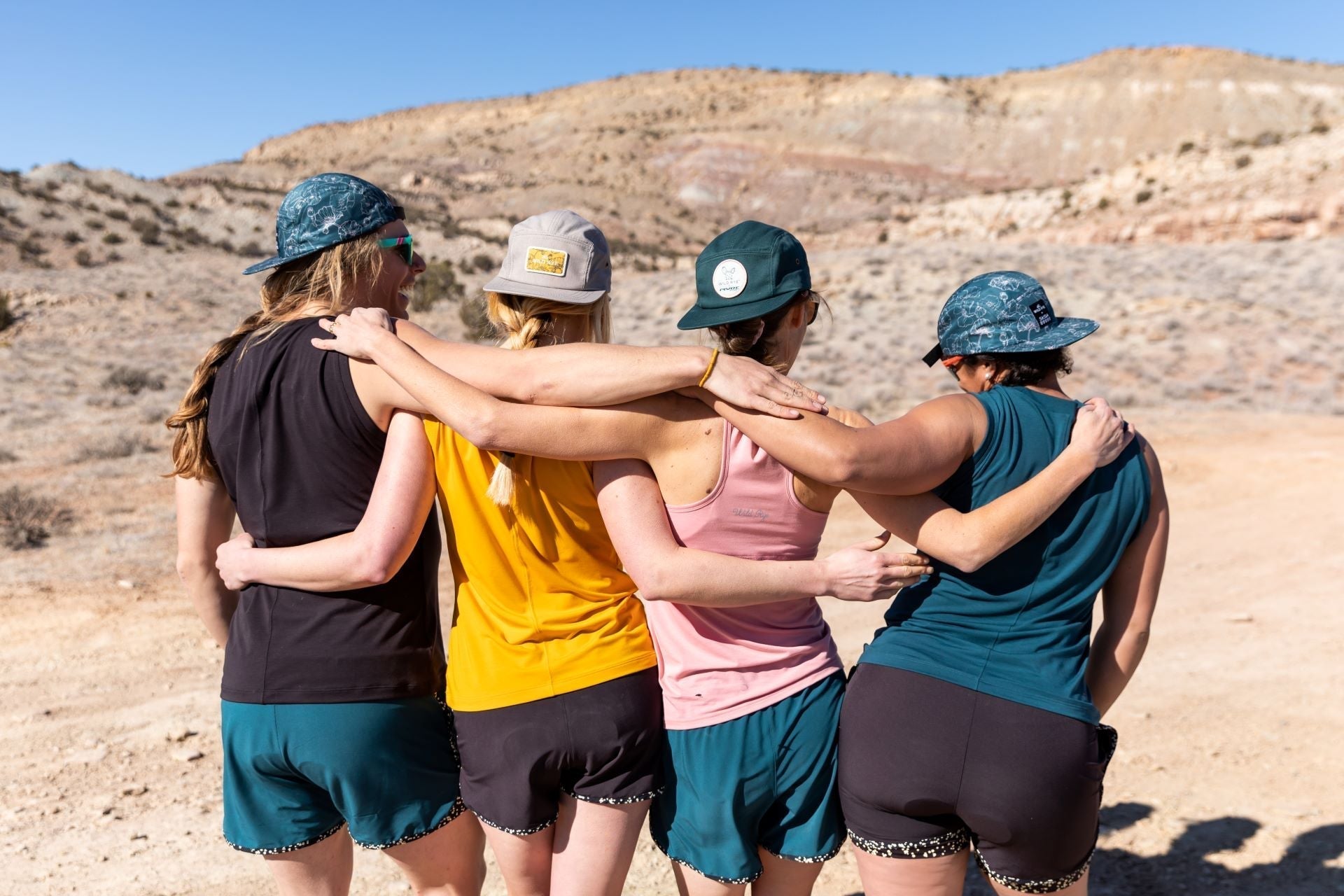 Four women in athletic wear standing together outdoors, embracing the spirit of biking and camaraderie.