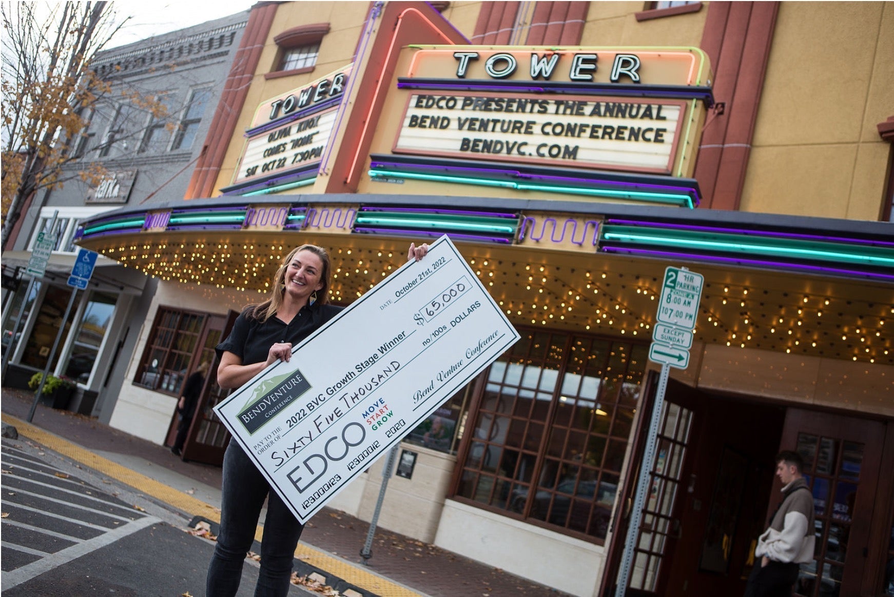 A woman holding a large check for $60,000 outside the Tower Theater during the EDCO Venture Conference.