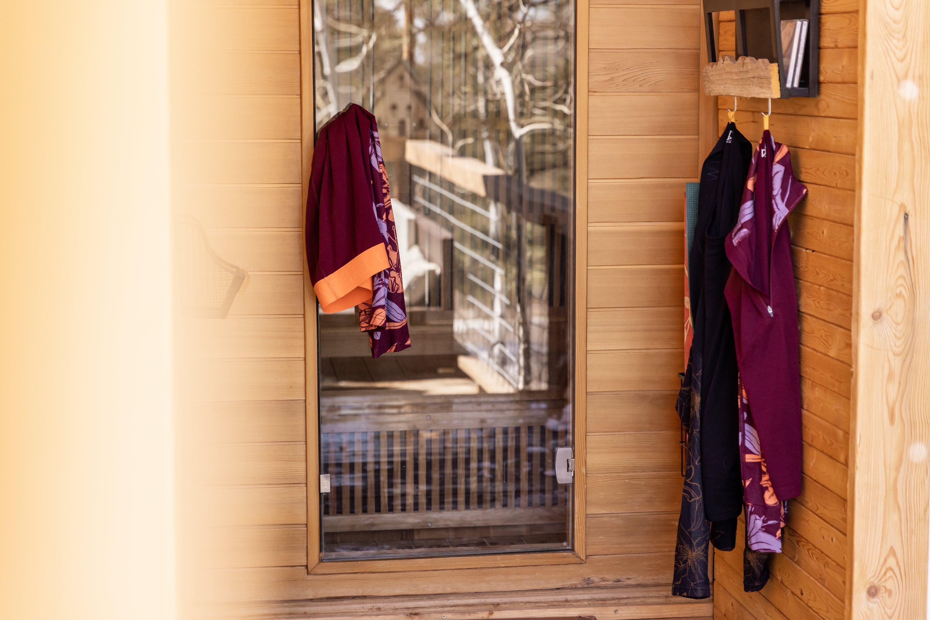 A wooden entryway with colorful clothing hanging on hooks