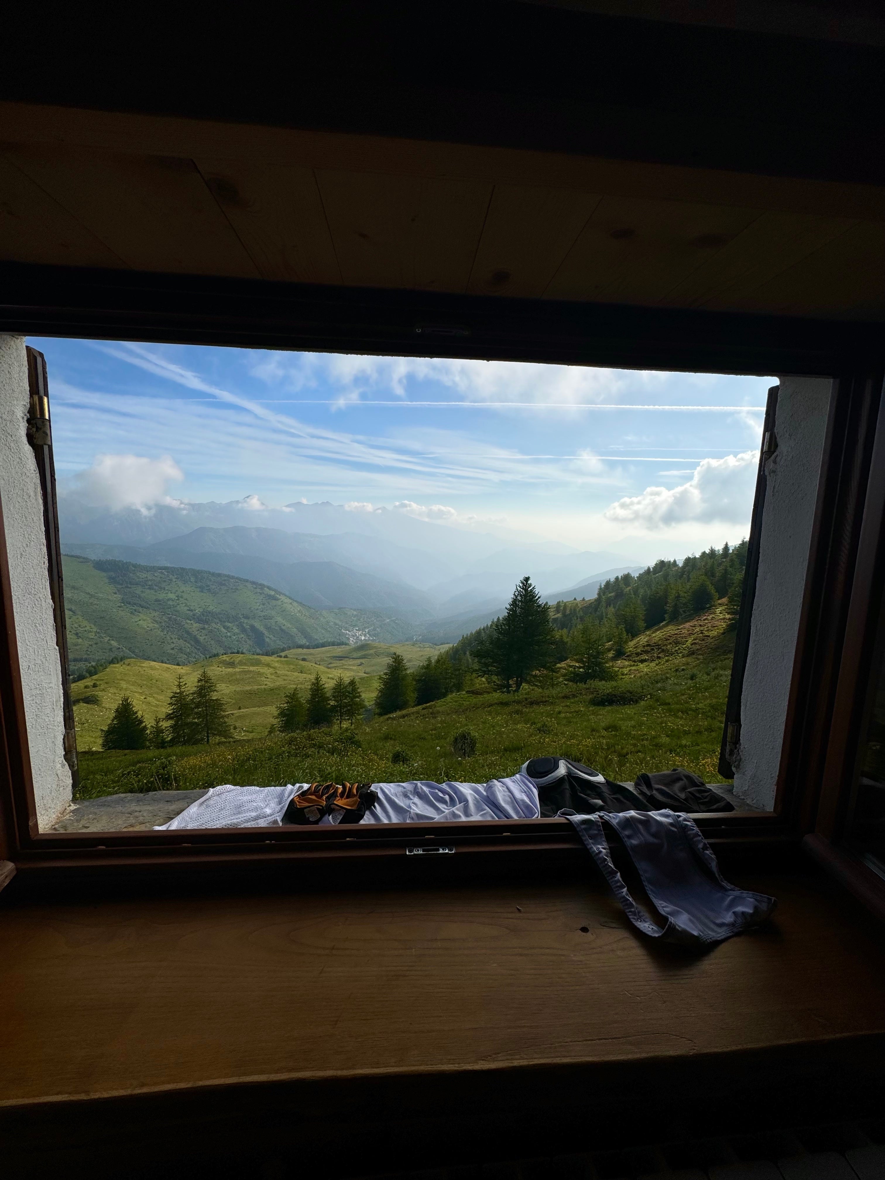 View of a mountainous landscape from a window, with trees and clouds in the distance