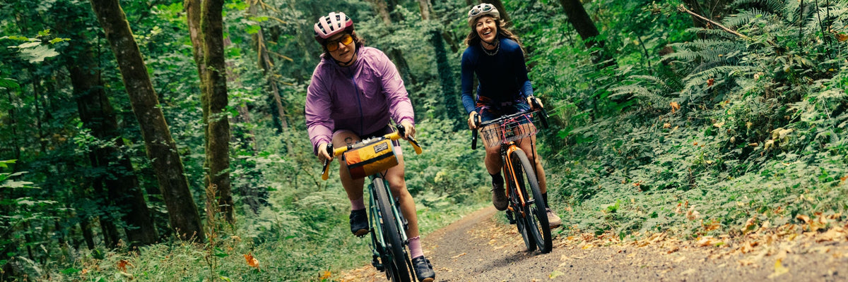 Person wearing a helmet standing with a mountain bike on a dirt trail under clear sky