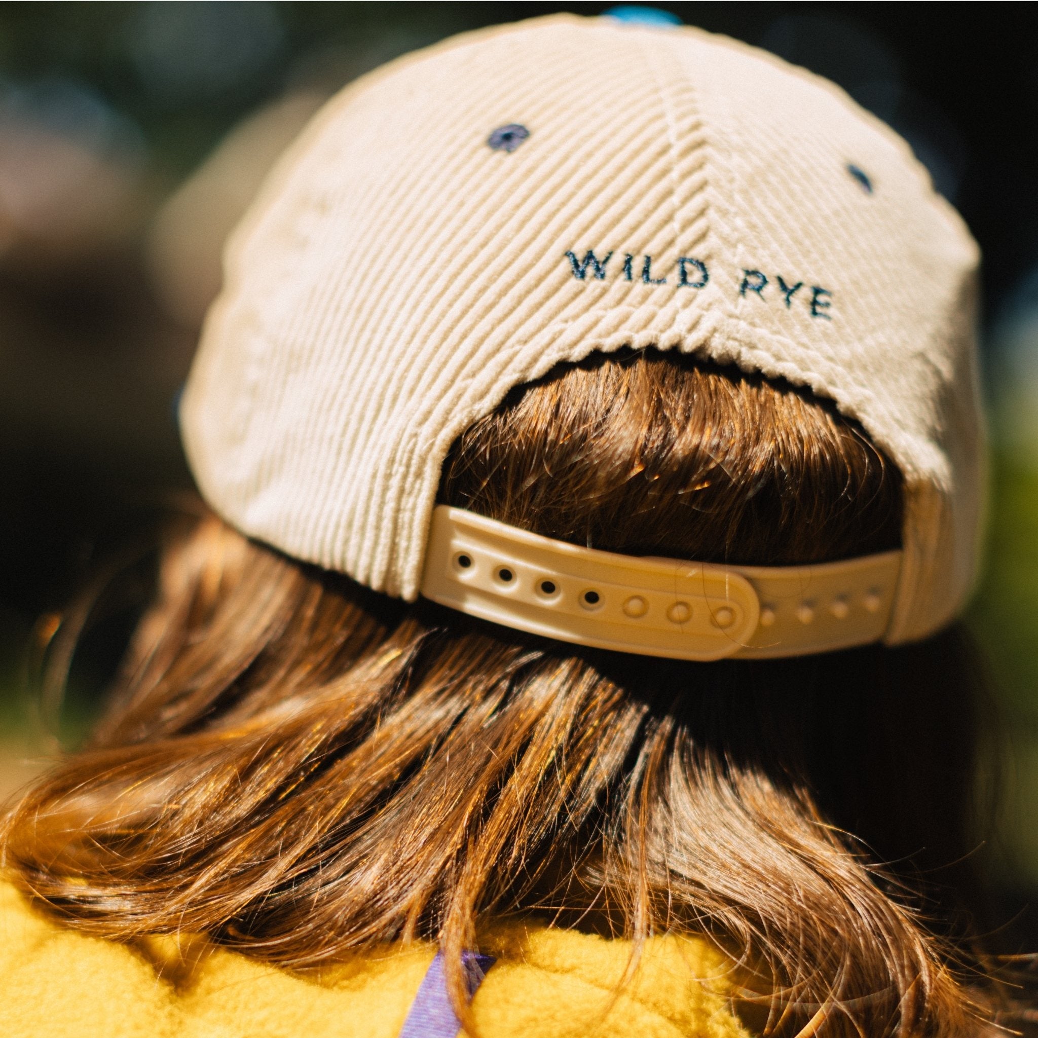 Person wearing a beige cap with Wild Rye embroidered on back