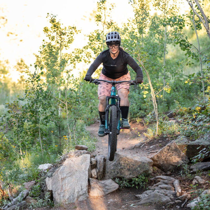 Woman riding rock feature in freel mountain bike short