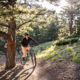 Woman riding through forest on mountain bike