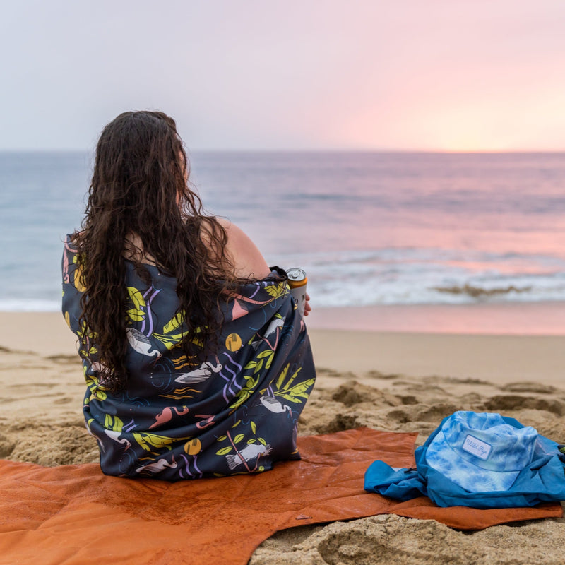 Woman wrapped in camp towel watching the sunset