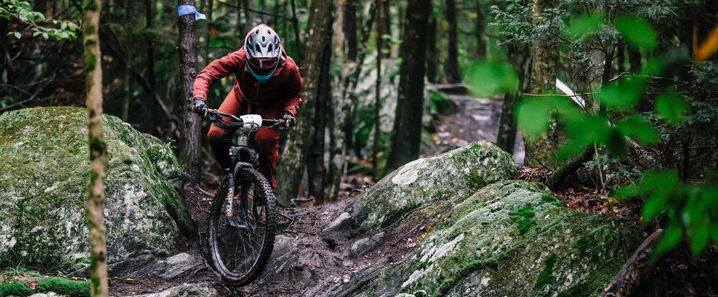 A mountain biker navigating a rocky trail in a forested area