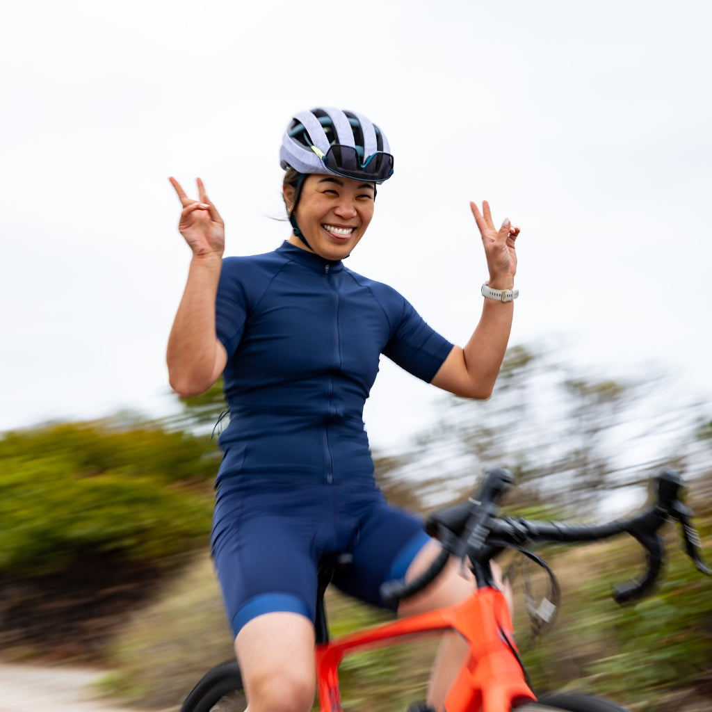 [Midnight] Woman riding gravel bike and holding up peace sign