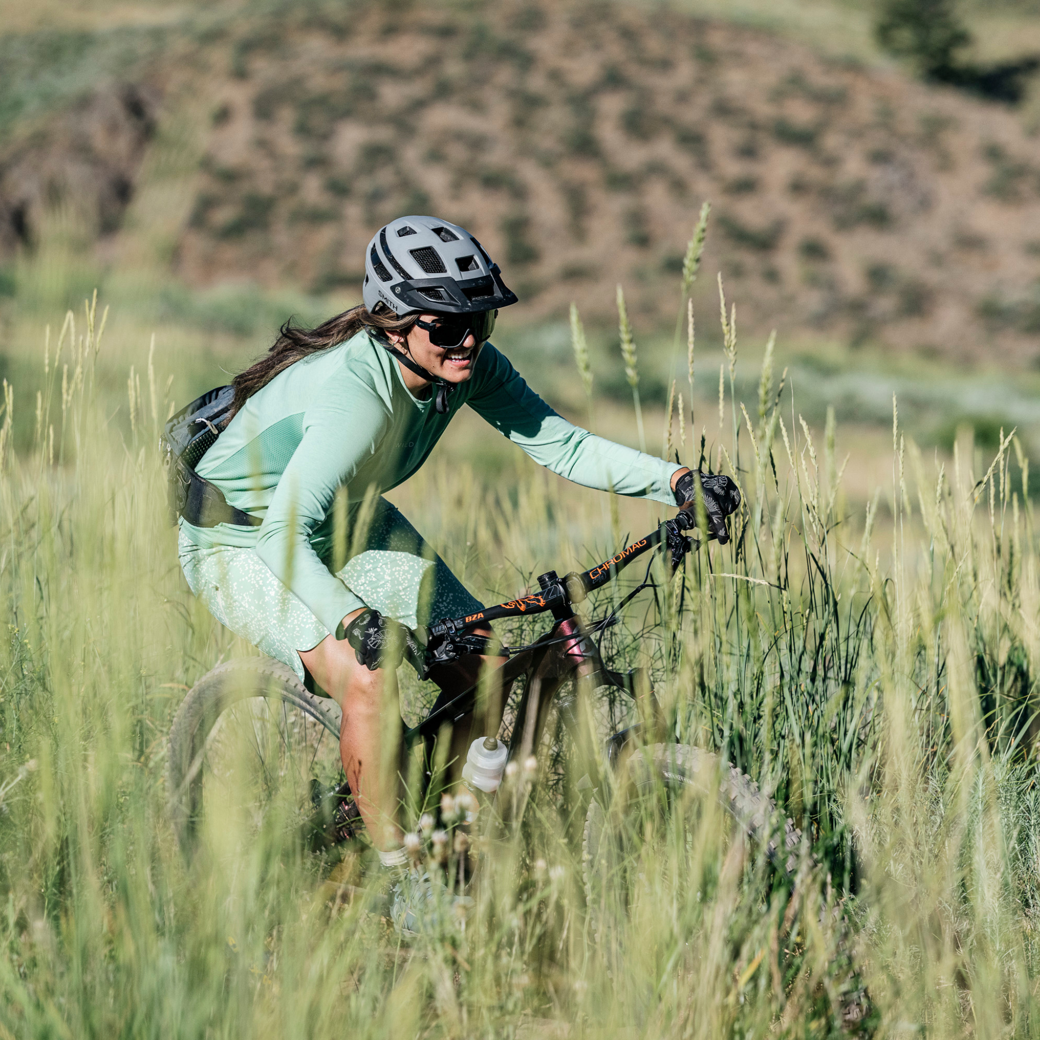 Woman biking downhill in green holly jersey