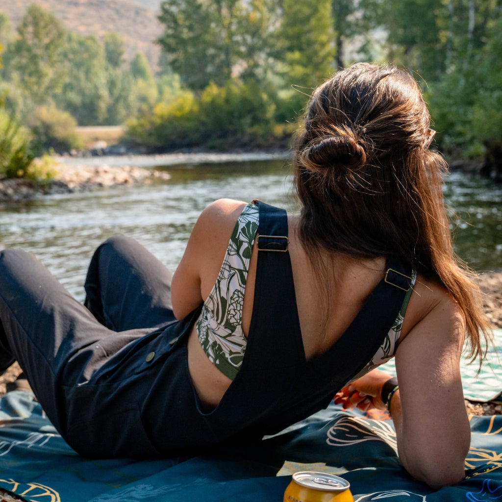 [Black] Woman lounging in overalls by the river