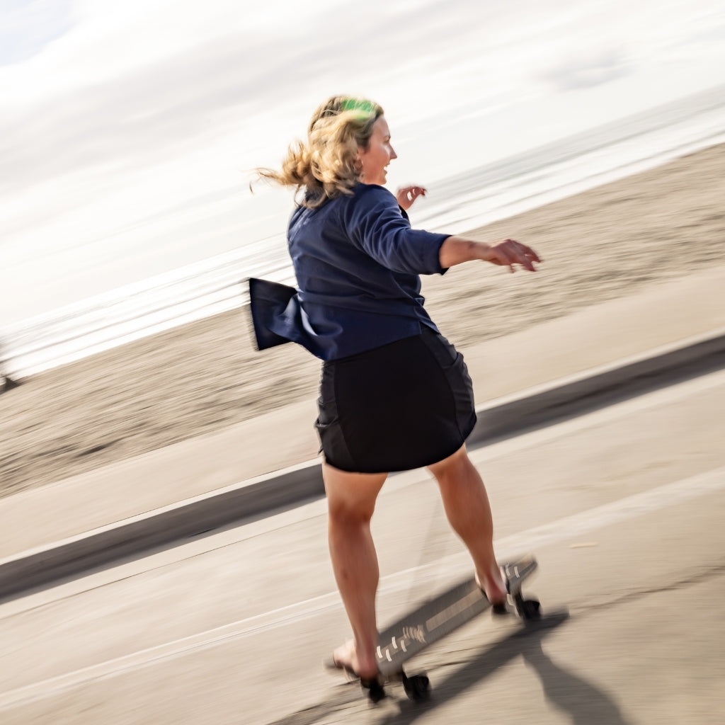 [Black] Woman skateboarding on boardwalk