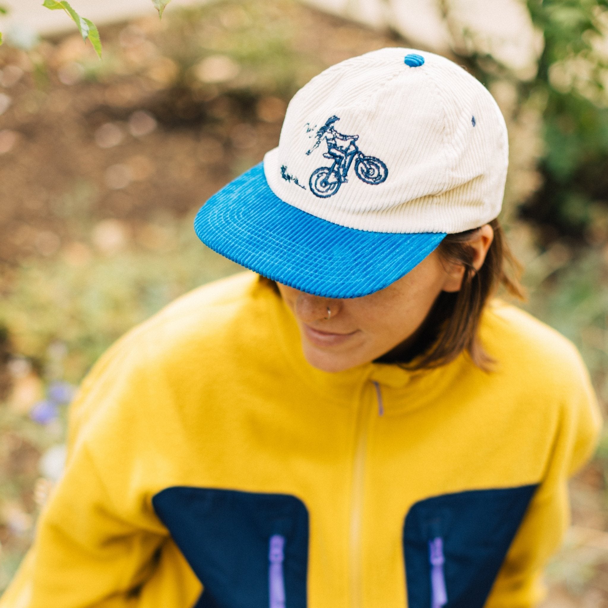 Person wearing a white and blue cap with a design, outdoors.