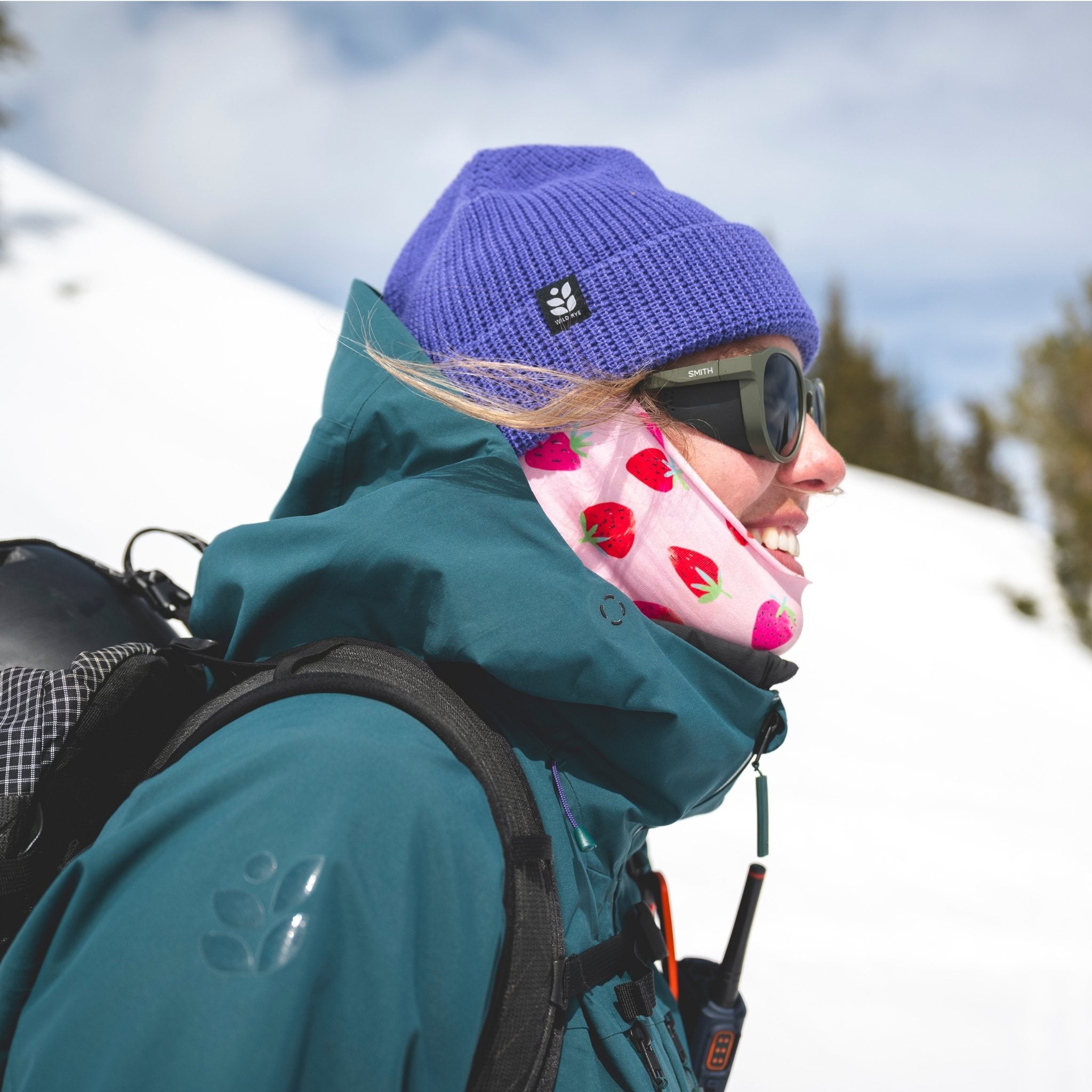 [Iris] Person in winter gear with a purple beanie and green jacket in a snowy landscape