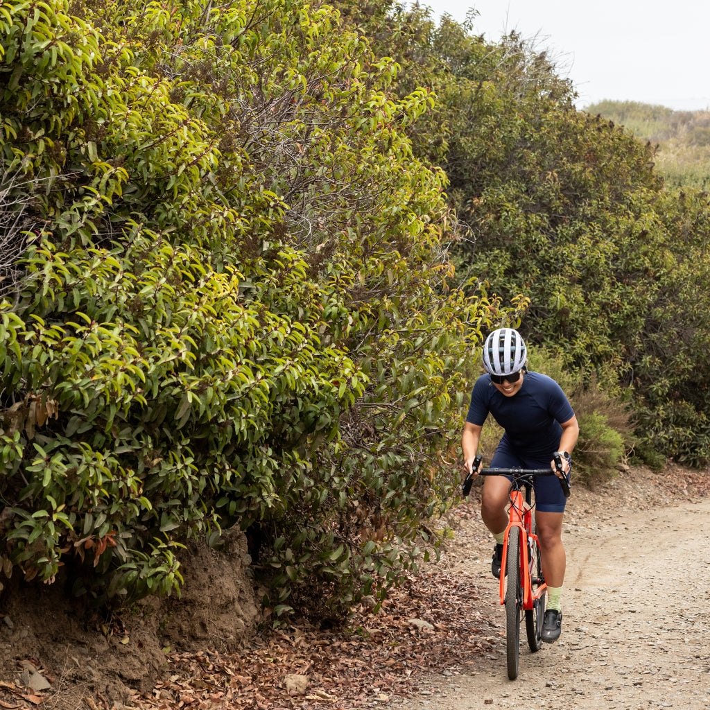 [Midnight] Woman biking uphill on gravel bike in alyssa chammy in  midnight