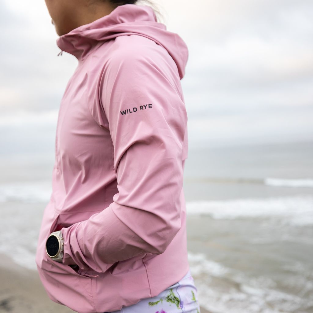 [Berry Blush] Woman wearing alden anorak in berry blush hiking by the ocean