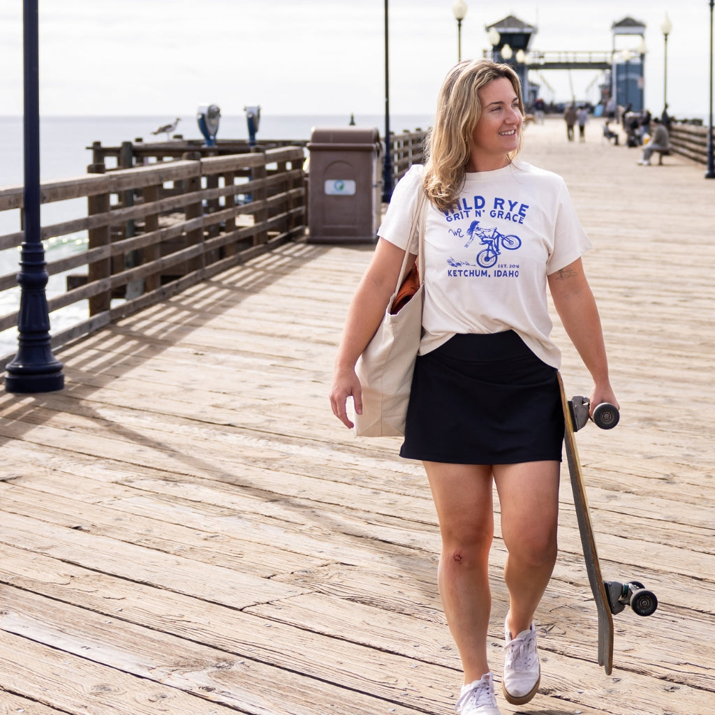 [Black] Woman walking with skateboard on boardwalk