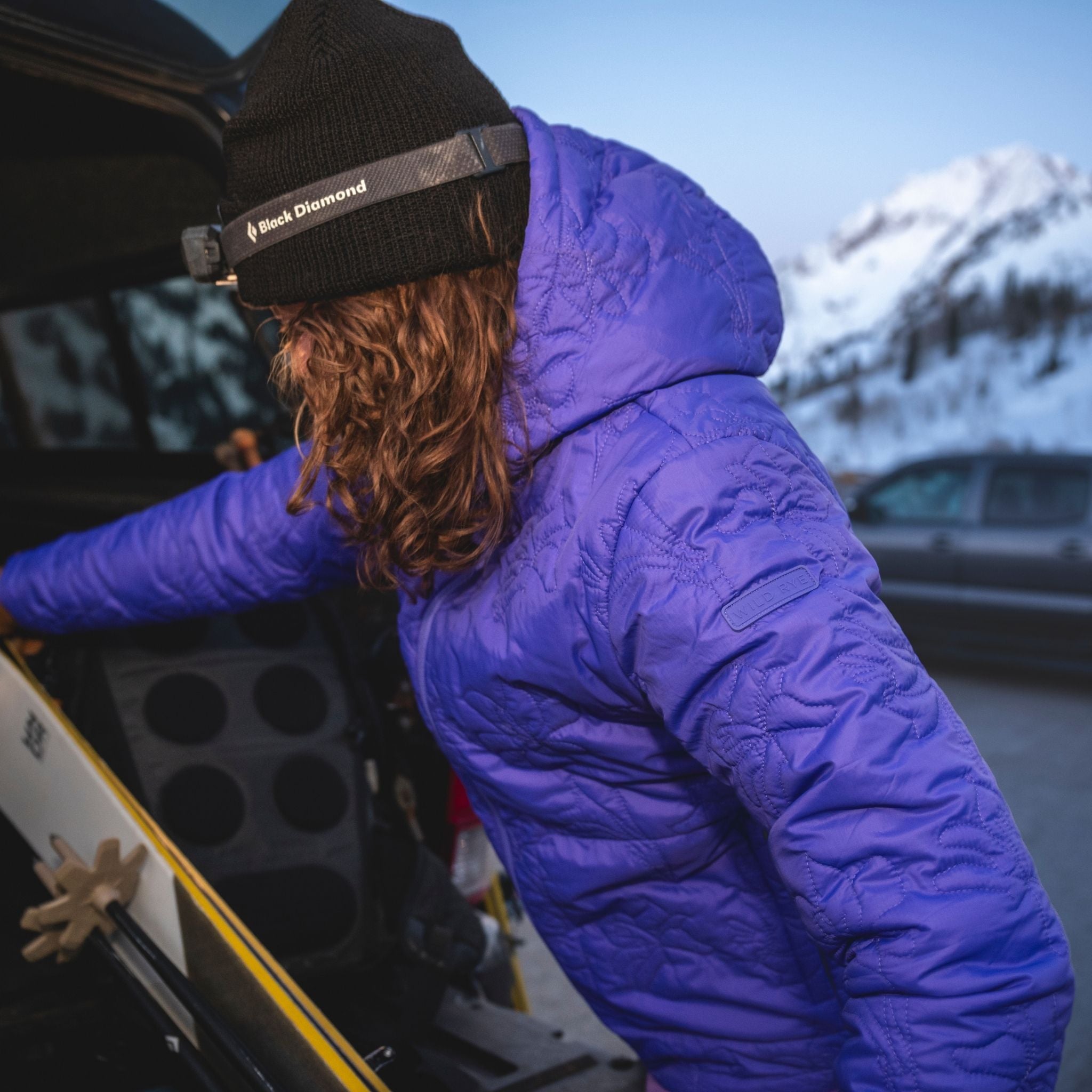 [Iris] Person in a purple jacket and black beanie putting skis into truck