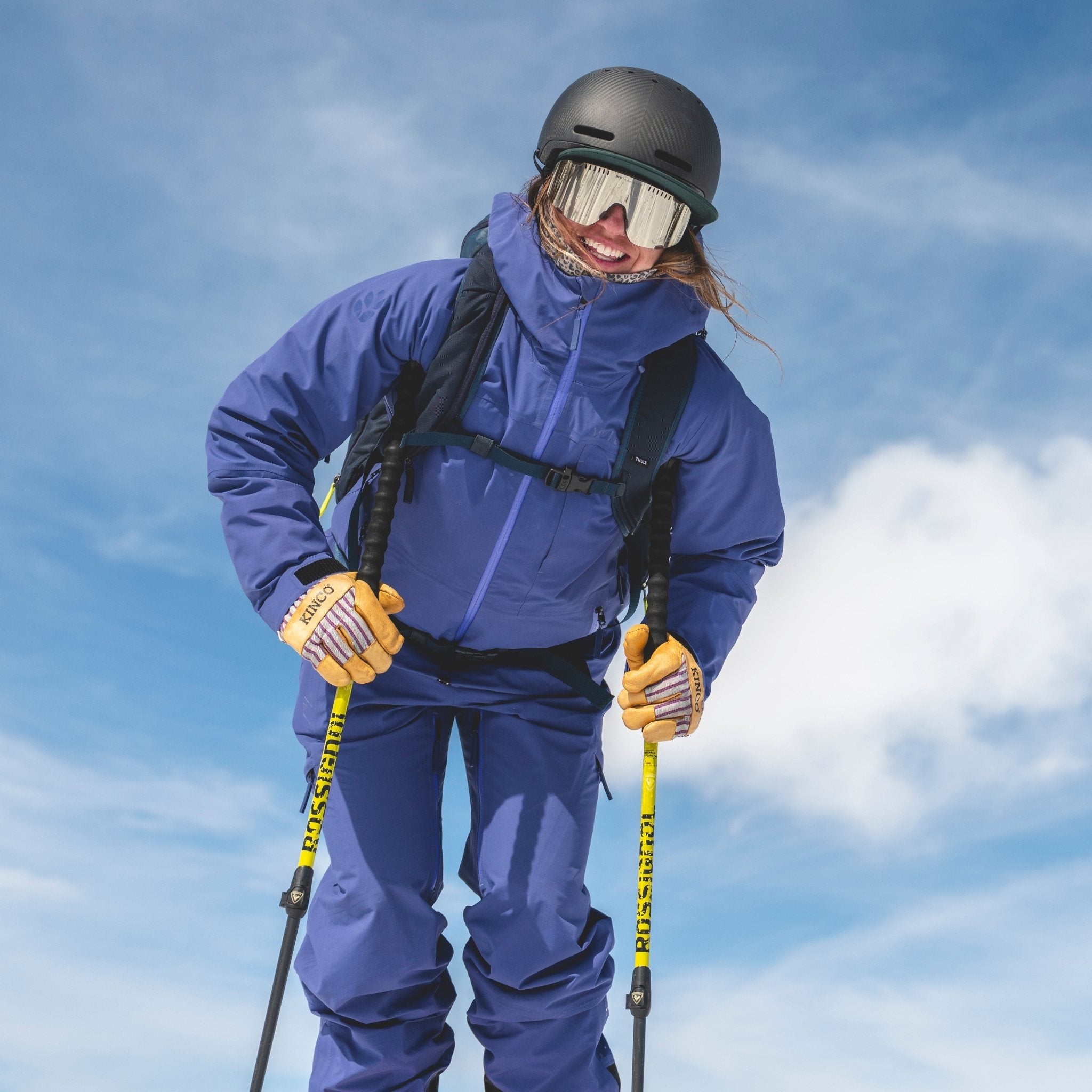 [Storm] Person in blue ski kit with yellow ski poles against a blue sky