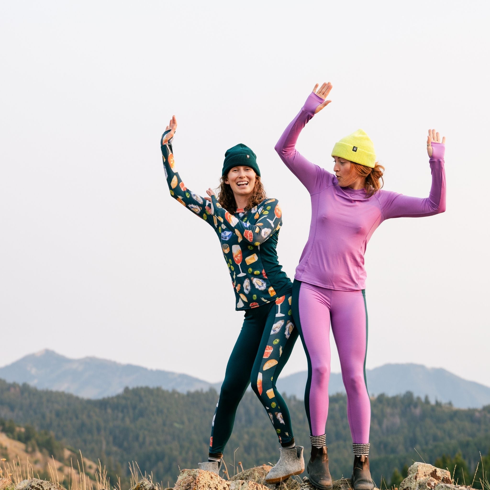 [Spruce Spuntini] Two people in colorful baselayer outfits with mountainous background