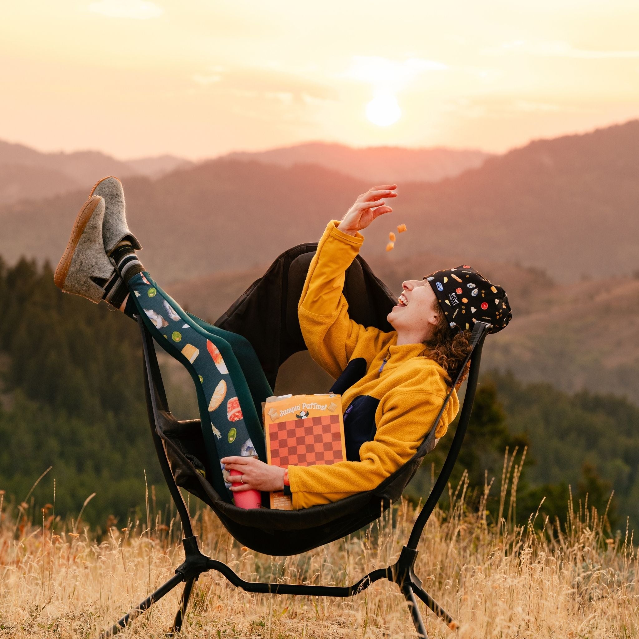 [Spruce Spuntini] Person sitting in a chair with a scenic mountain backdrop during sunset