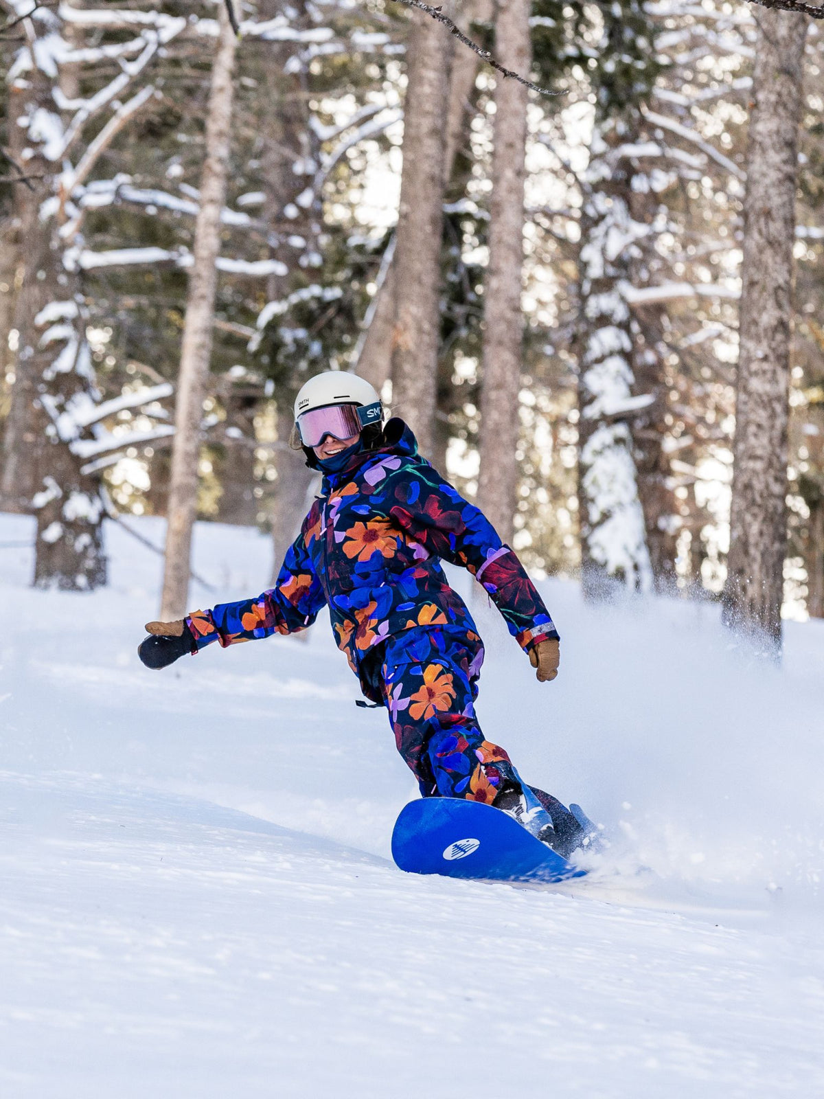 [Nightflora] Woman snowboarding through snowy trees in a nightflora floral Butterfield jacket and pant