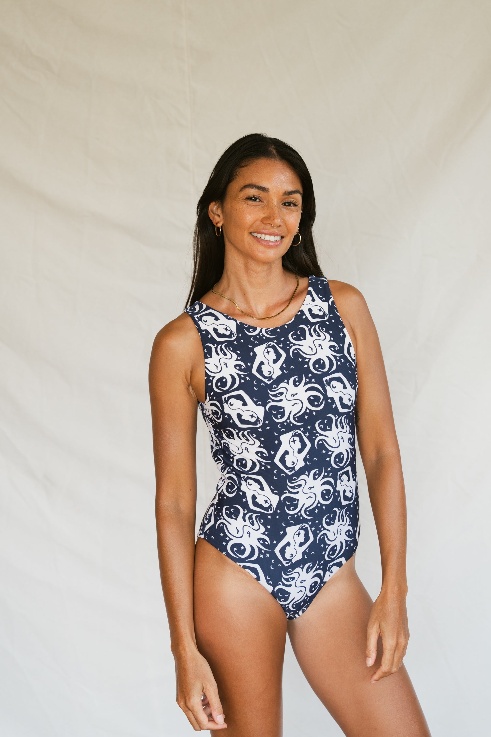 Woman wearing a navy blue swimsuit with white octopus-like pattern against a plain background