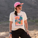 Woman standing in the desert wearing Cream cotton t shirt with colorful graphic that reads "women belong where decisions are made"