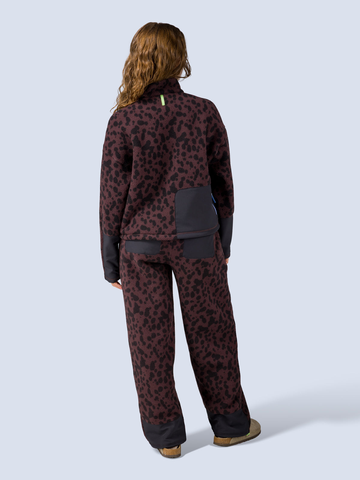 [Dapple] Model wearing the Banner Pant in brown leopard-print fleece with the matching zip jacket, full back view