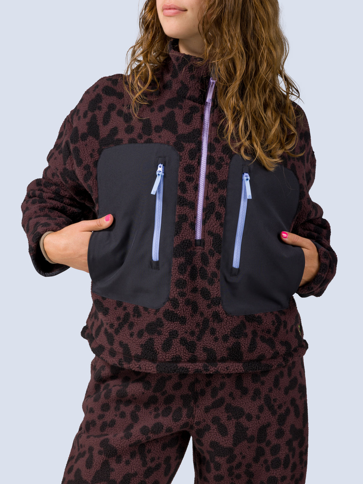 [Dapple] Close-up of the Banner 3/4 Zip Jacket's black zip pockets and lavender zipper pull on the brown leopard-print fleece
