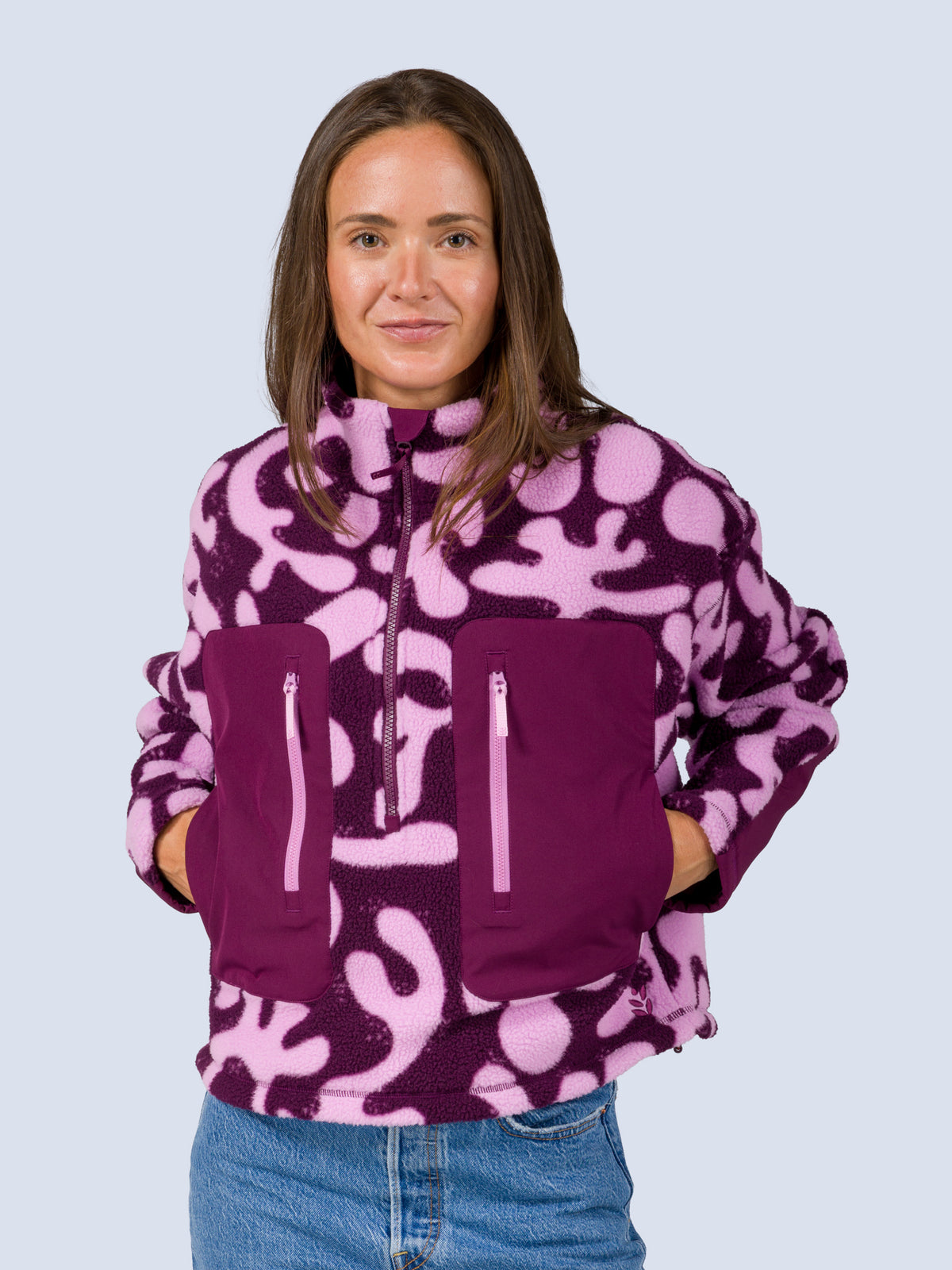 [Mulberry Reef] Close-up front view of a model wearing the Banner 3/4 Zip Jacket in purple and pink abstract-print fleece, hands tucked into the zip pockets