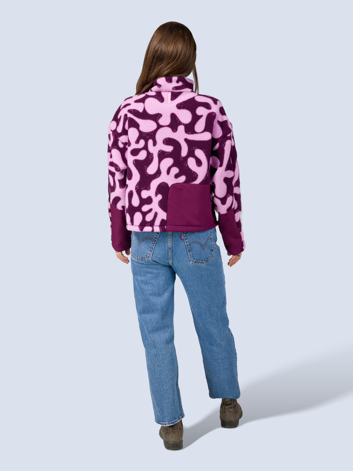 [Mulberry Reef] Model wearing the Banner 3/4 Zip Jacket in purple and pink abstract-print fleece with jeans, full back view