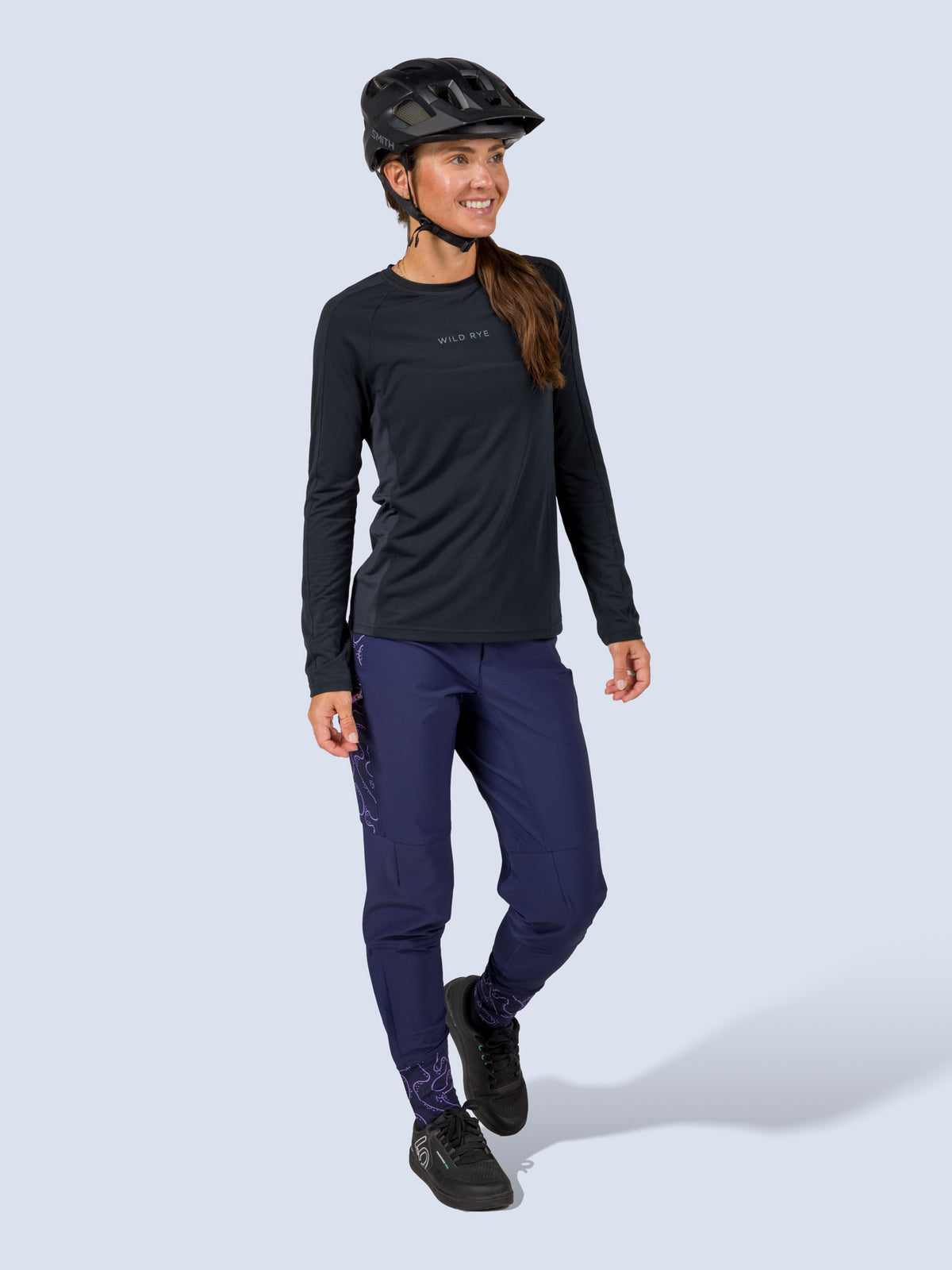 [Abyss Reef] Model wearing the Freyah Bike Pant in navy with a black long-sleeve top and helmet, walking in a front three-quarter view