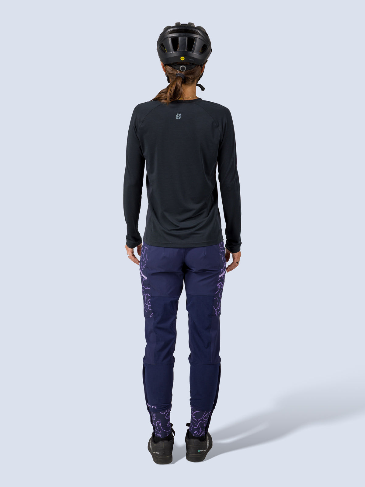 [Abyss Reef] Model wearing the Freyah Bike Pant in navy with a black long-sleeve top and helmet, full back view showing the purple print reinforced knees