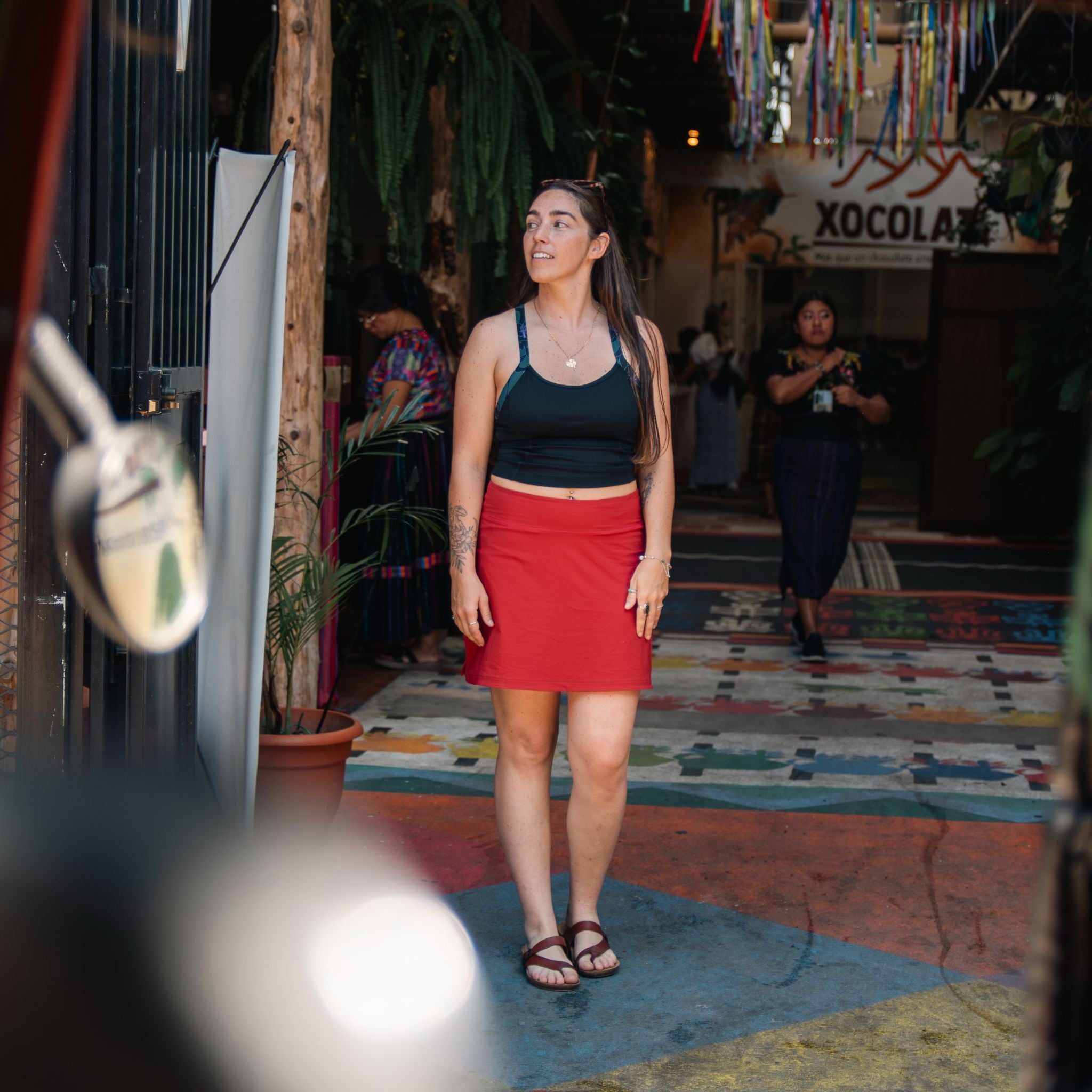 [Star Garnet] Woman in a red skirt and black top standing in a colorful indoor setting.