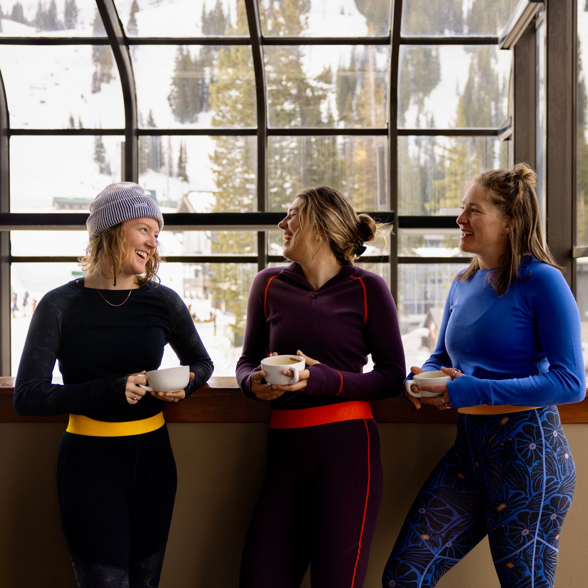 three women drinking coffee wearing wild rye baselayer sets