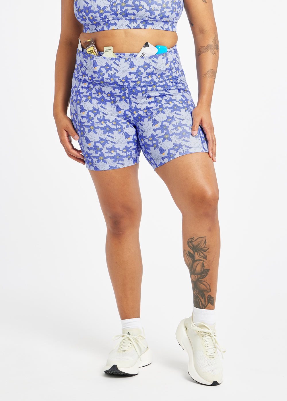 Person wearing blue floral athletic shorts and showing stash pocket waist design