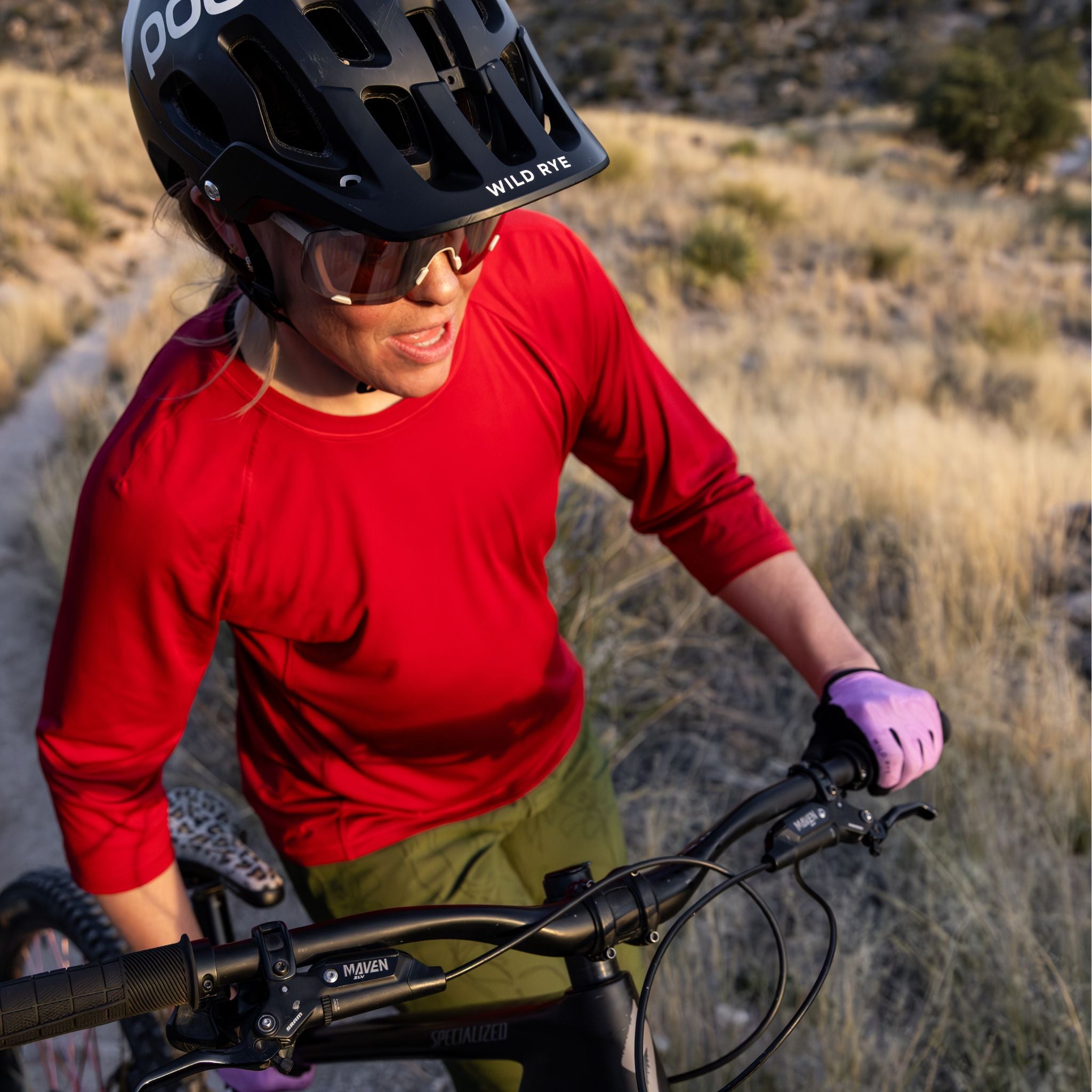 [Star Garnet] Person on a mountain bike wearing a red shirt, black helmet, and purple gloves in a desert setting.