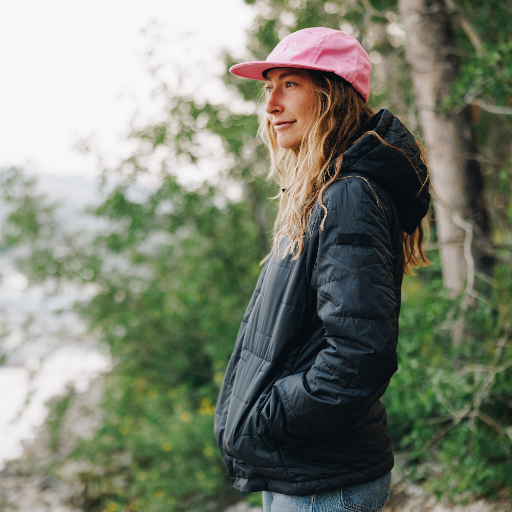 Woman wearing black insulated jacket, standing with hands in pockets