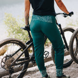 [Pine] Woman standing by bike in Freyah Pant Pine