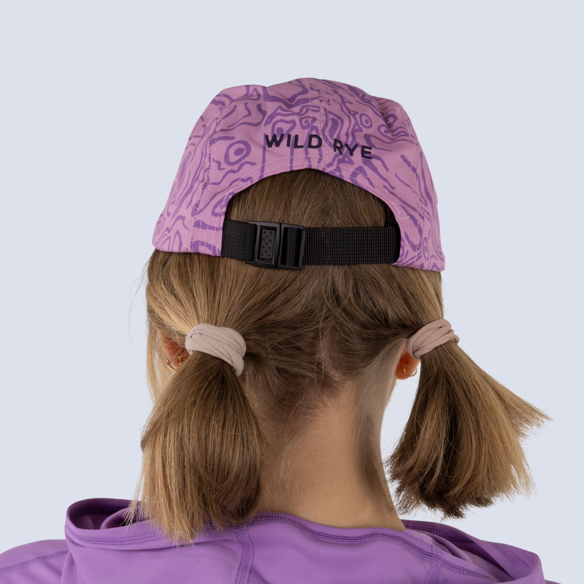 Person wearing a pink baseball cap with "wild rye" printed at back