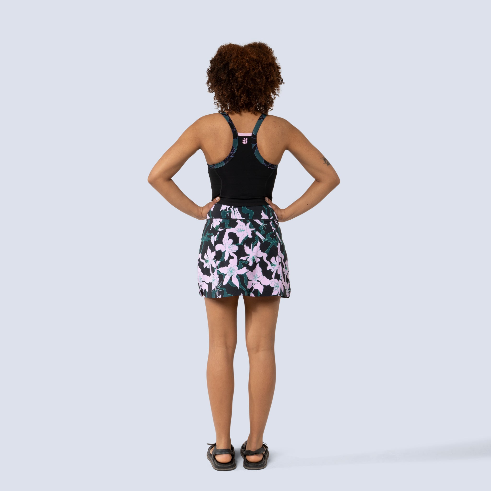[Black Aquila Bloom] Parker Skort in black with pink floral pattern, on model back full body view
